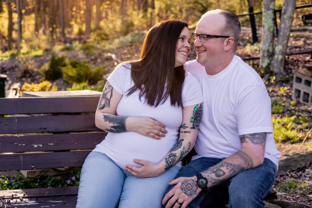 Mara and Michael on a bench, holding her belly and looking at each other. 