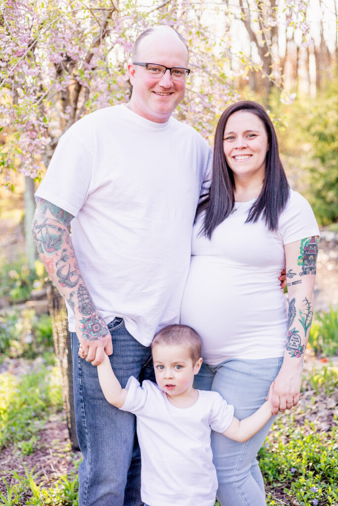 Michael, Mara and tanner in white T-shirts standing in front of a cherry blossom tree. 